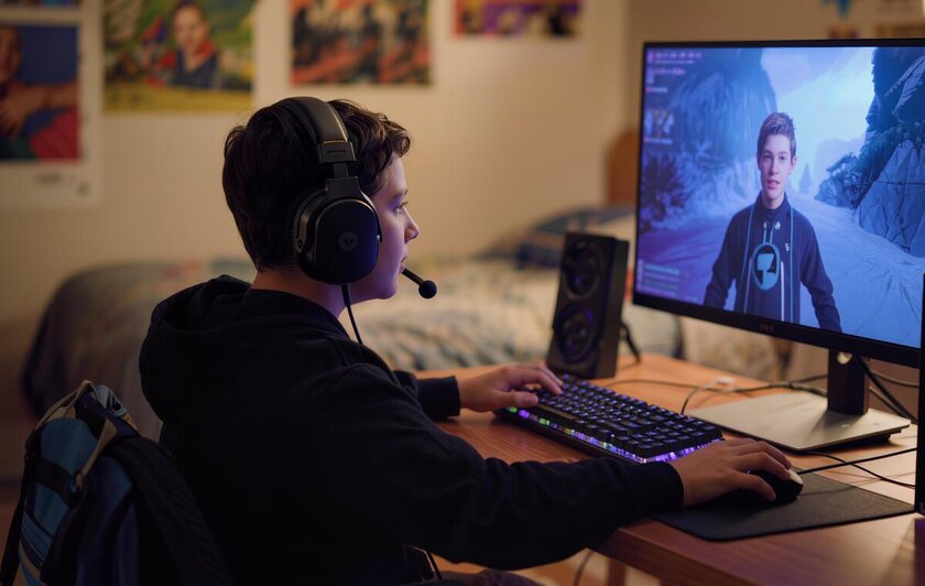 A teenager wearing headphones gaming on a desktop computer