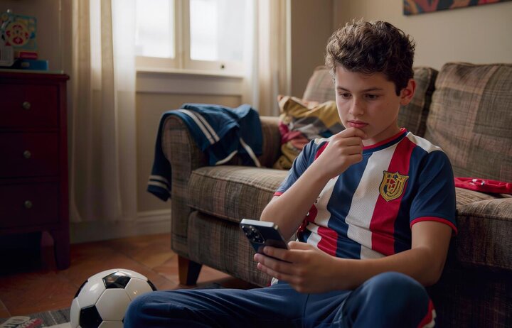 A teenager sitting on a sofa using their phone